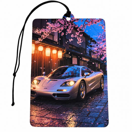 McLaren F1 inspired car air freshener featuring a silver supercar on a Japanese street with pink cherry blossoms, glowing lanterns and black hanging cord.