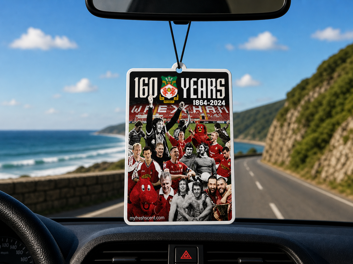 Car air freshener celebrsting 160 of wrexham afc, hanging from a car's rearview mirror on a road trip.
