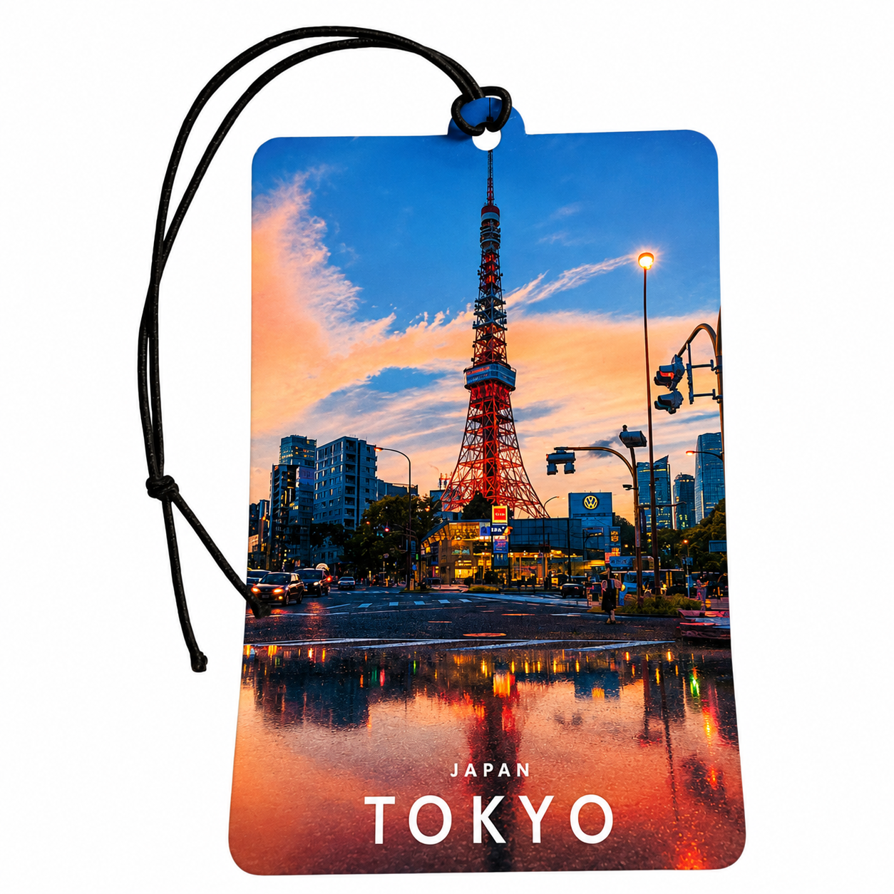 A rectangular car air freshener featuring a colorful photograph of the Tokyo Tower at sunset with city reflections in the water. The tag has rounded corners, a black hanging cord, and the words 'JAPAN TOKYO' printed at the bottom.