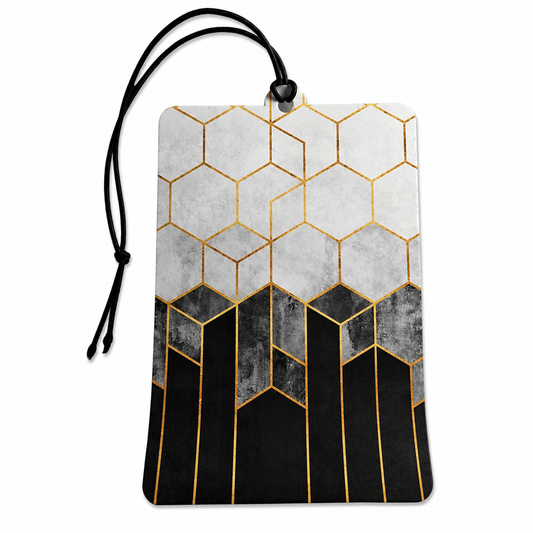 A rectangular luggage tag or car air freshener with a black hanging cord, featuring a geometric pattern of gold hexagons on a light gray top half and a black geometric pattern on a dark gray bottom half.