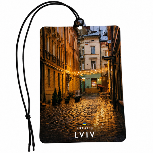 A rectangular car air freshener featuring a printed photograph of a cobblestone street in Lviv, Ukraine, with a black hanging cord and the text 'UKRAINE LVIV' printed at the bottom.