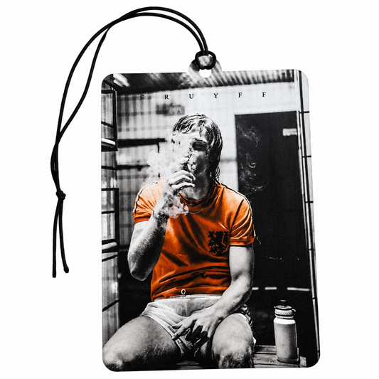 A rectangular car air freshener or luggage tag with a black hanging loop, featuring a black-and-white photo print of johan cruyff smoking with his orange shirt highlighted in color, shown on a plain white background.