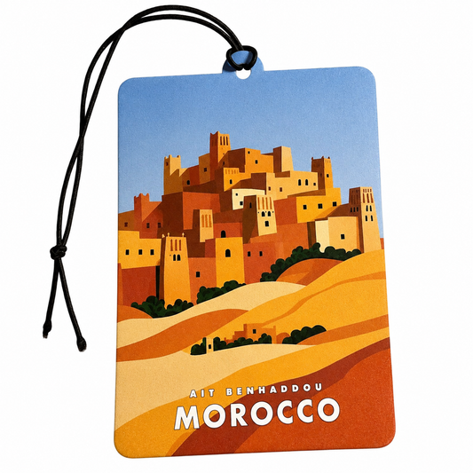 A rectangular travel tag or car air freshener with a black hanging cord, featuring a stylized illustration of Ait Benhaddou in Morocco under a blue sky, with the text 'AIT BENHADDOU MOROCCO' at the bottom.